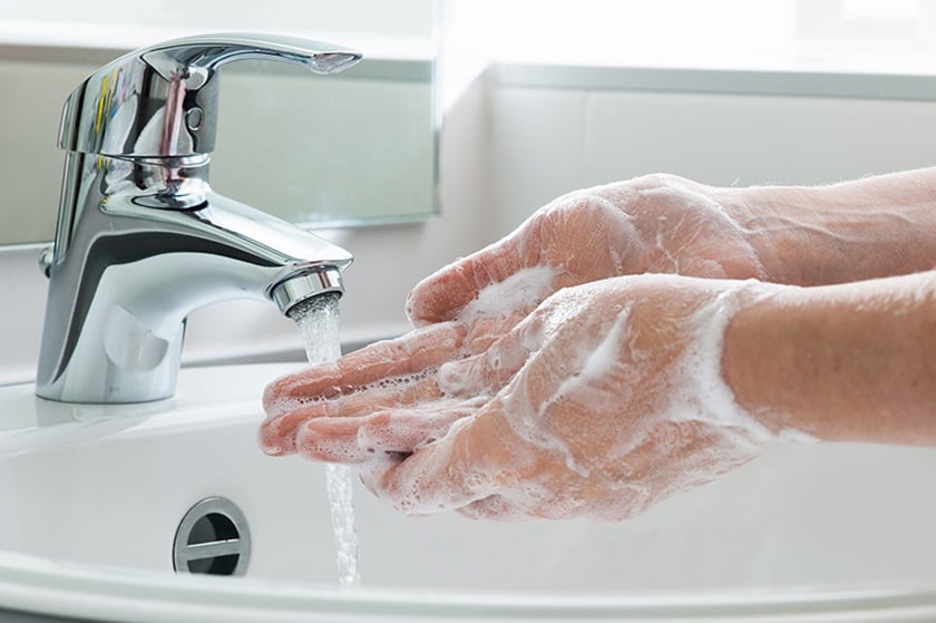 Close-up of soaped hands under a running faucet.