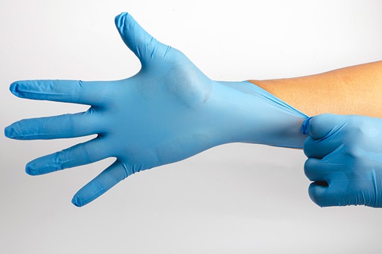 Hands putting on blue examination gloves.