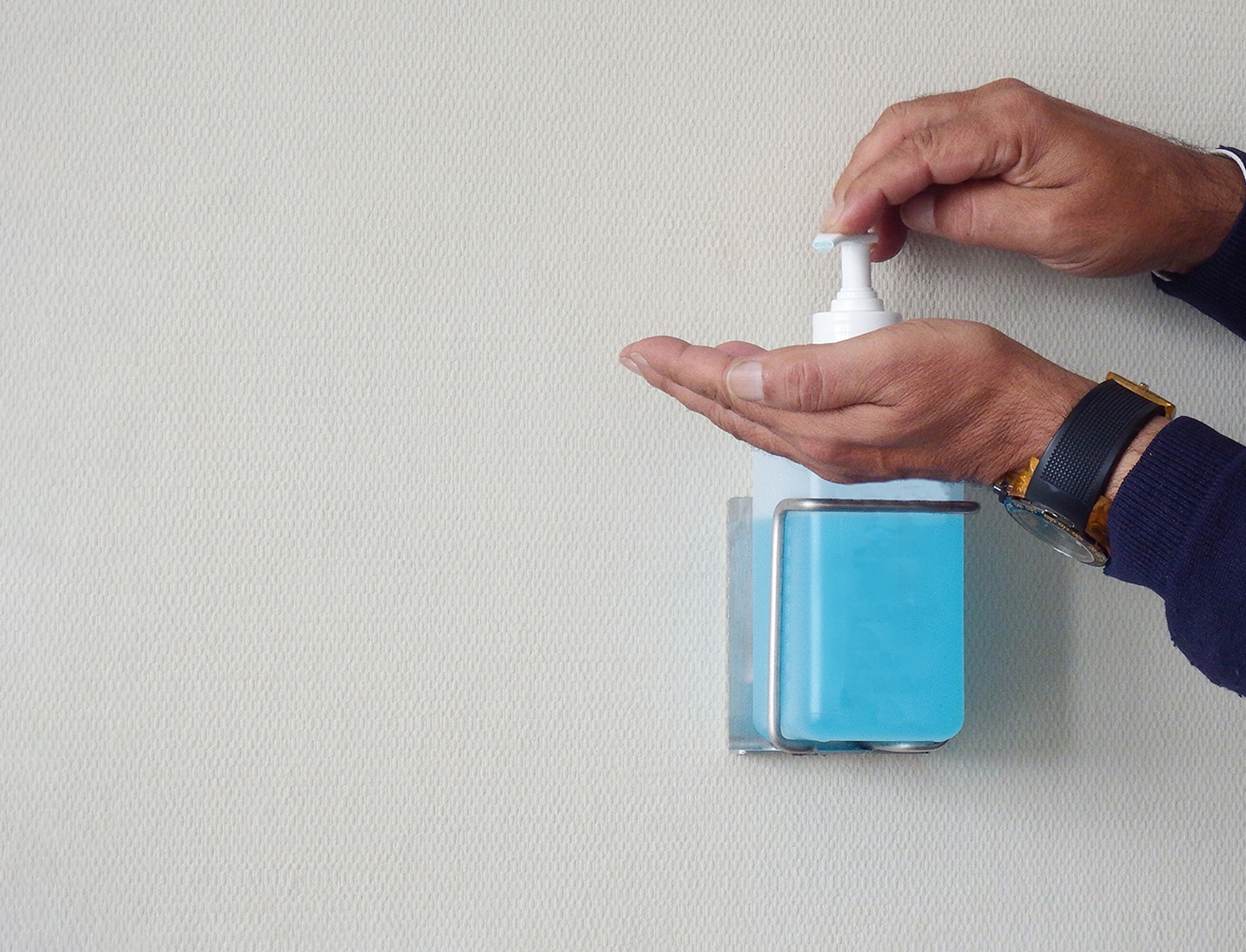 A man disinfects his hands at a disinfectant dispenser.