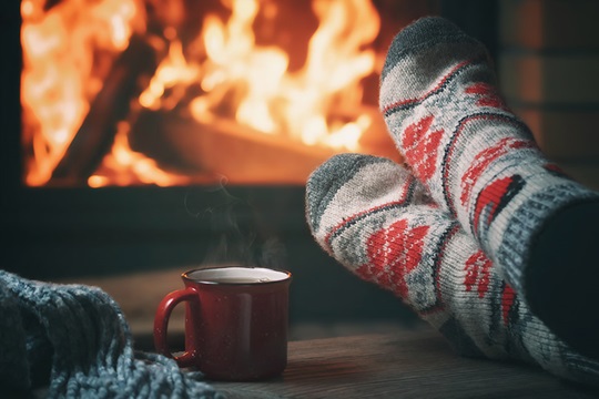 Feet in thick woolen socks in front of a fireplace.