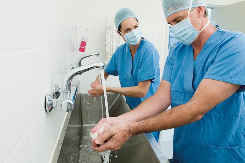 Two doctors wash their hands with antimicrobial soap and water before an operation.
