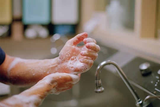 A doctor scrubs his hands and forearms with soap and water.