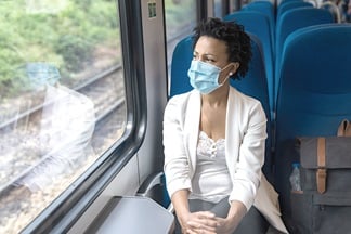 Woman on train wearing mouth-nose protection