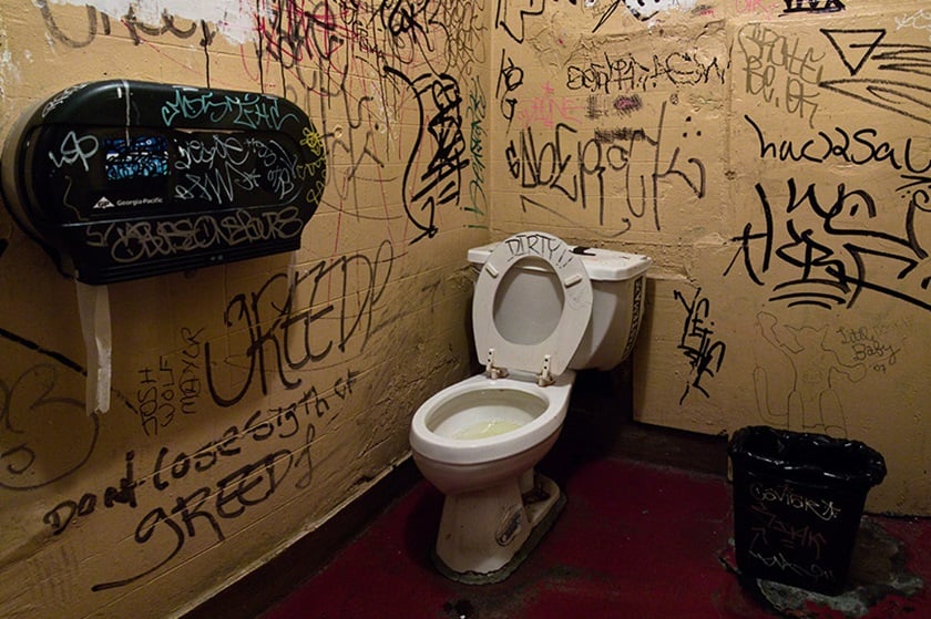 A public toilet stained with graffiti.